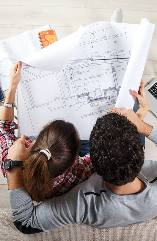 overhead view of a man an women looking over large blueprints of a home construction project