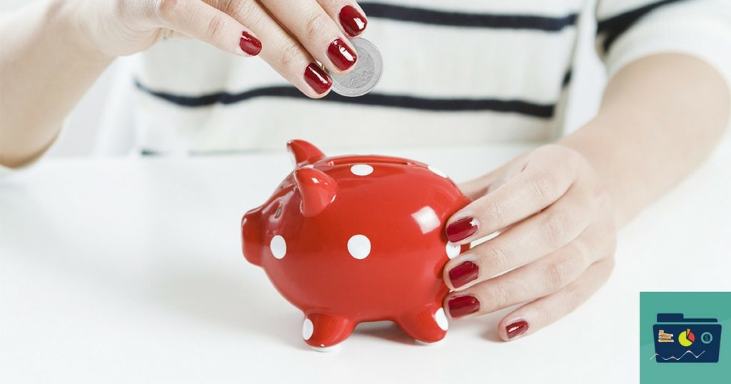 close up of a woman's hand with red painted nails, holding a red ceramic piggy bank and a quarter