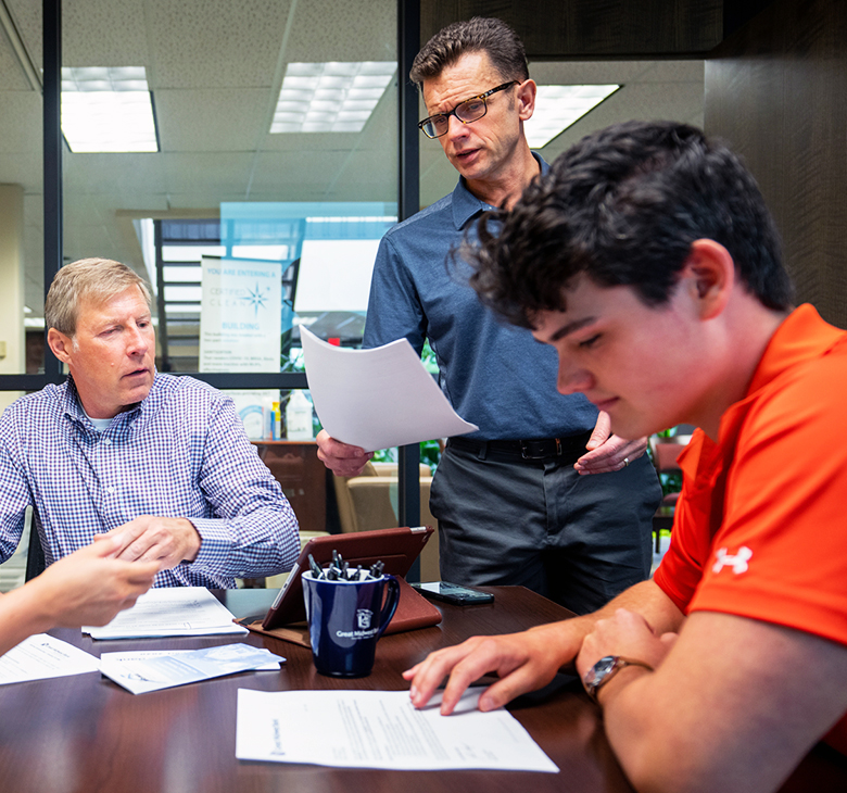 Great Midwest Bank Senior Vice President of Mortgage Operations Jon Reetz and Loan Officer John Hugo review paperwork with a young customer.
