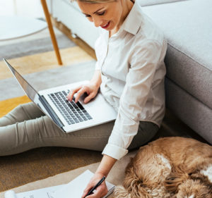 mature woman sitting on the floor working laptop next to a dog