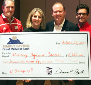 Great Midwest Bank Senior Vice President of Mortgage Operations Jon Reetz stands next to University of Wisconsin Madison's Men's Basketball Coach Greg Gard and his wife. Reetz is presenting the Gards with a large check made out to the Gards' charitable organization, Garding Against Cancer.