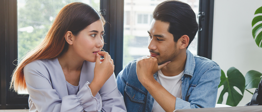 a young couple looks at each other pensively